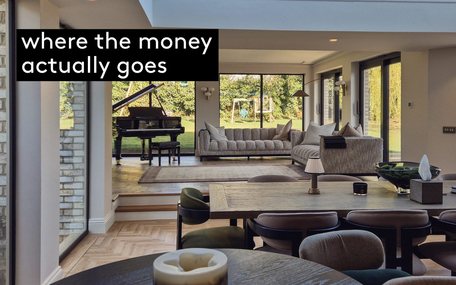 An open-plan living and dining space in a high-end West Yorkshire extension, with sliding glazing onto the garden, herringbone oak flooring and a grand piano beyond