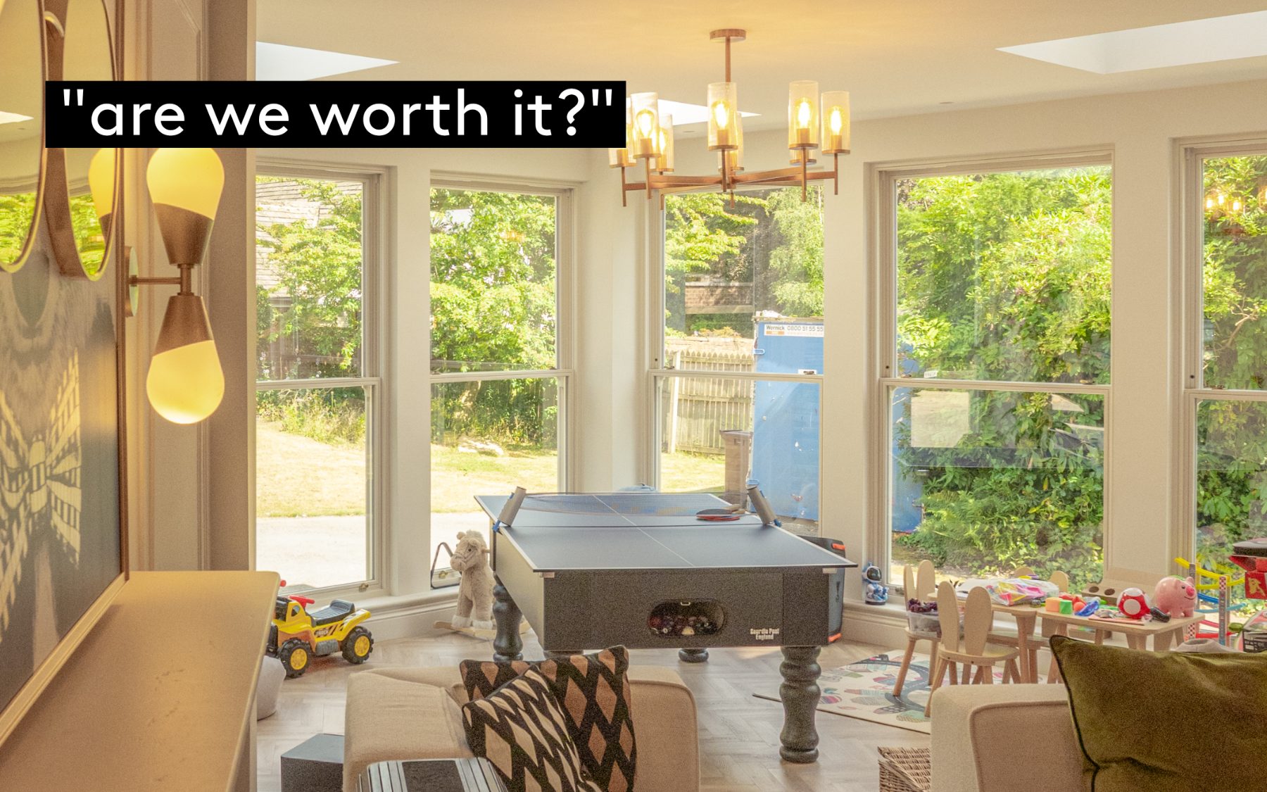 A family playroom in a bright bay-windowed extension, with a table tennis table, toys and a child-height table looking out to the garden