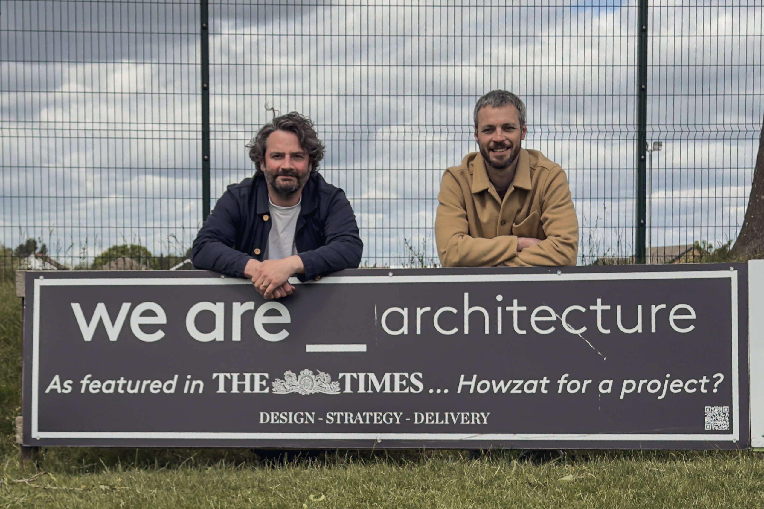 Andrew Clapham and Jack Davey, the two directors of we are _ architecture studio, behind their we are _ architecture sponsor board at Morley Cricket Club, Leeds