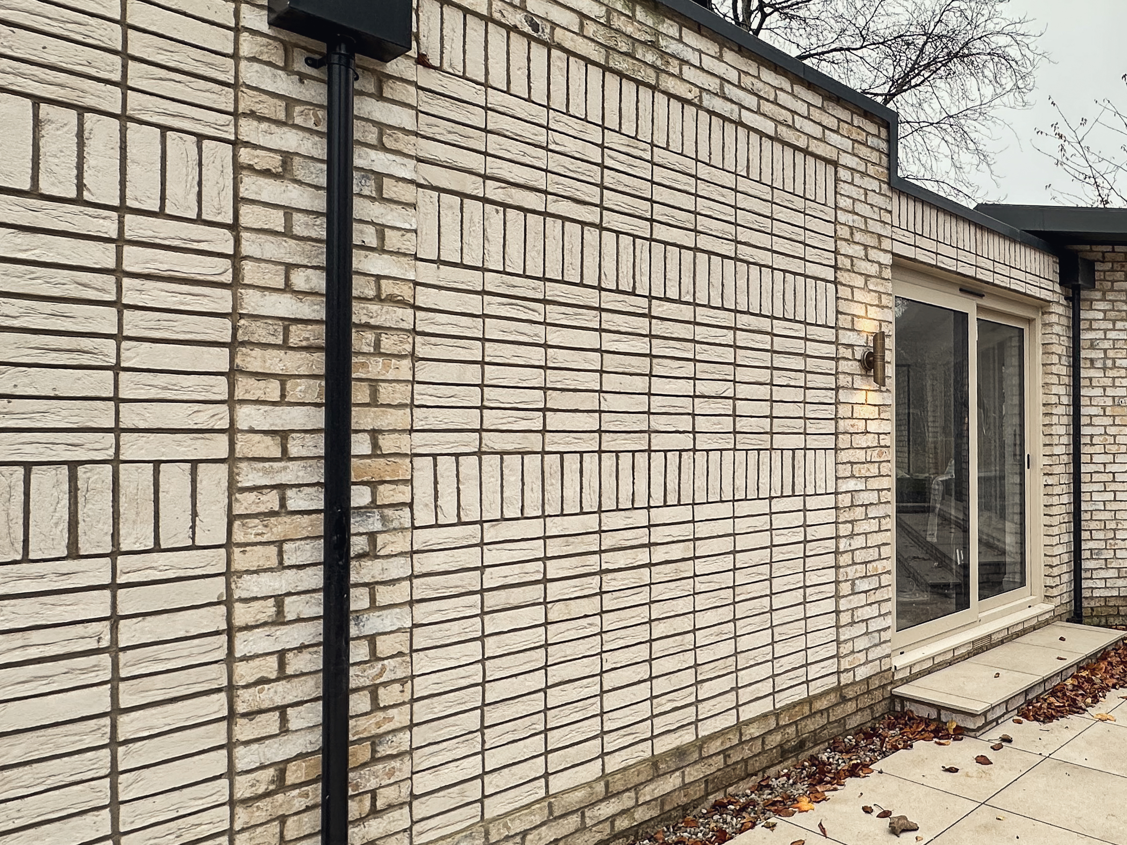 Stacked-bond brick panels with coursing that reduces as the wall rises, a sculptural garden wall detail in Roundhay, Leeds