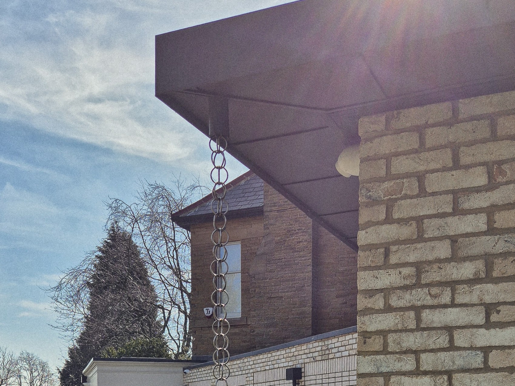 Sculptural metal rain chain, a kusaridoi, on the primary brick pillar in place of a downpipe, Roundhay, Leeds